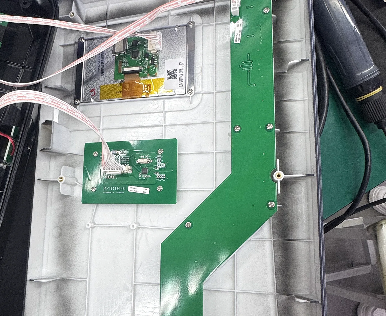 The enclosure open on the bench, showing the light-guide board, the reader board and the display module wired with ribbon cables